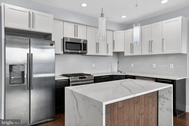 a kitchen with stainless steel appliances a sink a stove a microwave a refrigerator a sink and cabinets