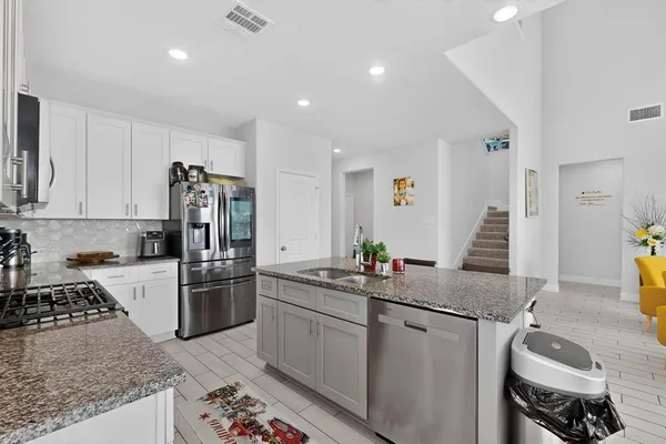 a kitchen with granite countertop a sink stove and refrigerator