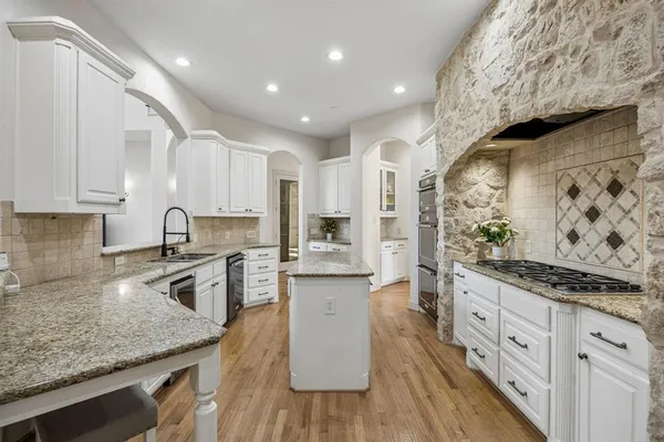 a kitchen with stainless steel appliances granite countertop a lot of counter space and wooden floors