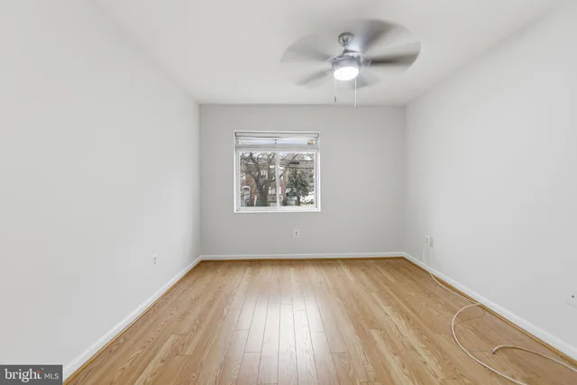 an empty room with a window and a fan