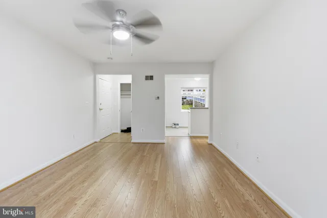 a view of an empty room with window and wooden floor