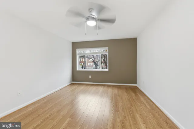 an empty room with wooden floor chandelier fan and windows