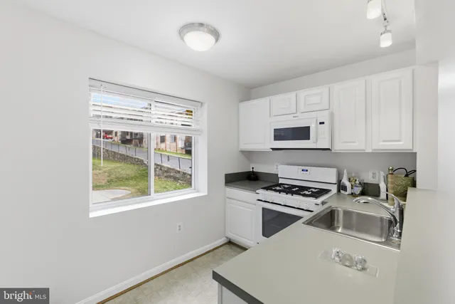 a kitchen with granite countertop a stove a sink and a microwave