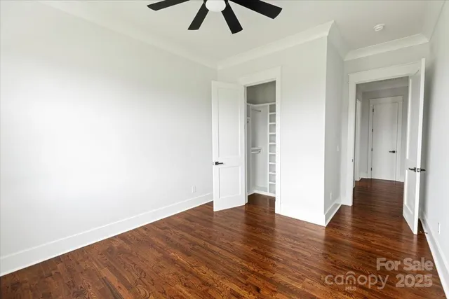 an empty room with wooden floor ceiling fan and windows