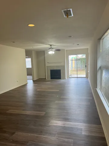 a view of an empty room with wooden floor and a fireplace