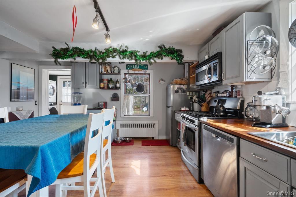 217-19 39th Avenue Queens, NY 11361 - Photo 9 of 38 a kitchen with stainless steel appliances granite countertop a stove a refrigerator a oven a dining table and chairs with wooden floor
