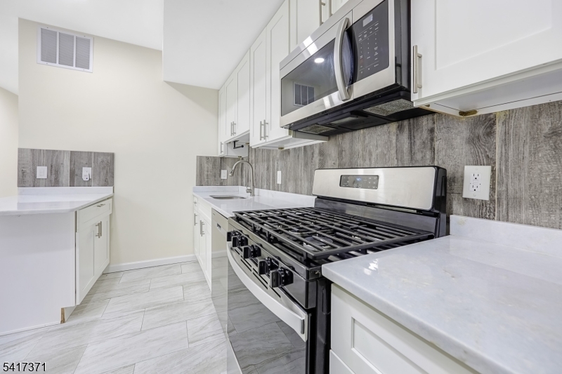 88 Devon Street Kearny, NJ 07032 - Photo 15 of 16 a kitchen with stainless steel appliances granite countertop a stove and a microwave