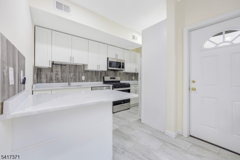 88 Devon Street Kearny, NJ 07032 - Photo 7 of 16 a kitchen with kitchen island white cabinets and stainless steel appliances