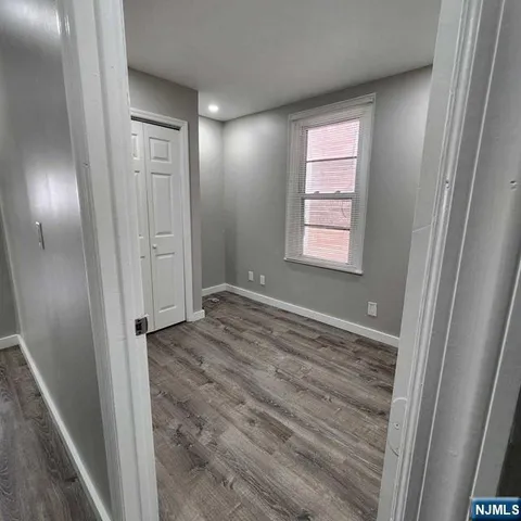 a view of hallway with window and wooden floor