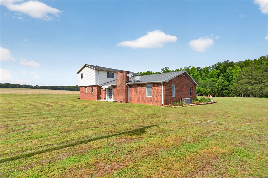 145 State Rd S-4-935 Pendleton, SC 29670 - Photo 28 of 47 A well-maintained brick and siding structure stands amidst a sprawling green expanse, offering serene rural living.