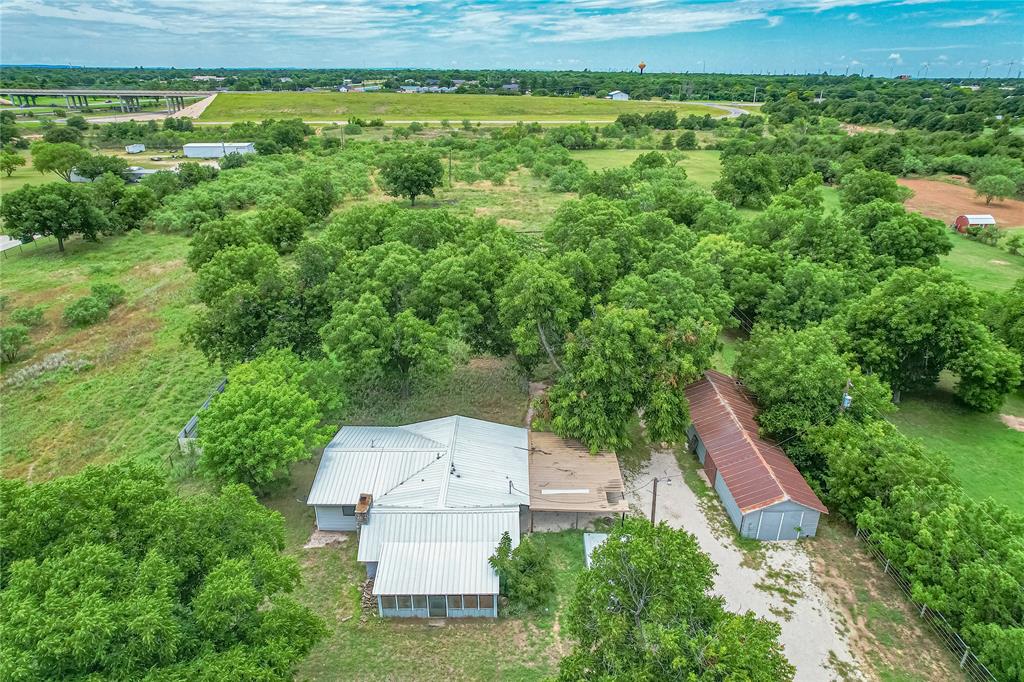 510 Hamby Road Clyde, TX 79510 - Photo 11 of 34 Expansive property featuring a single-story residence with a metal roof, a screened porch, and a detached outbuilding with a corrugated metal roof