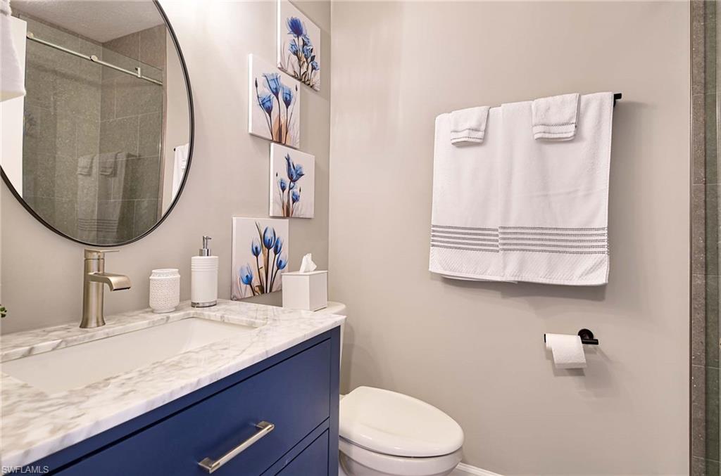 9022 Michael Circle, Unit 2210 Naples, FL 34113 - Photo 16 of 36 a bathroom with a granite countertop toilet sink and mirror