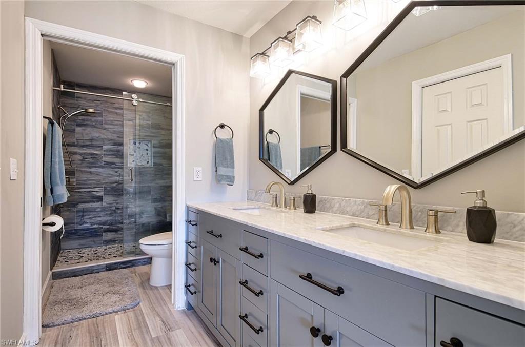 9022 Michael Circle, Unit 2210 Naples, FL 34113 - Photo 20 of 36 a bathroom with a double vanity sink and a mirror