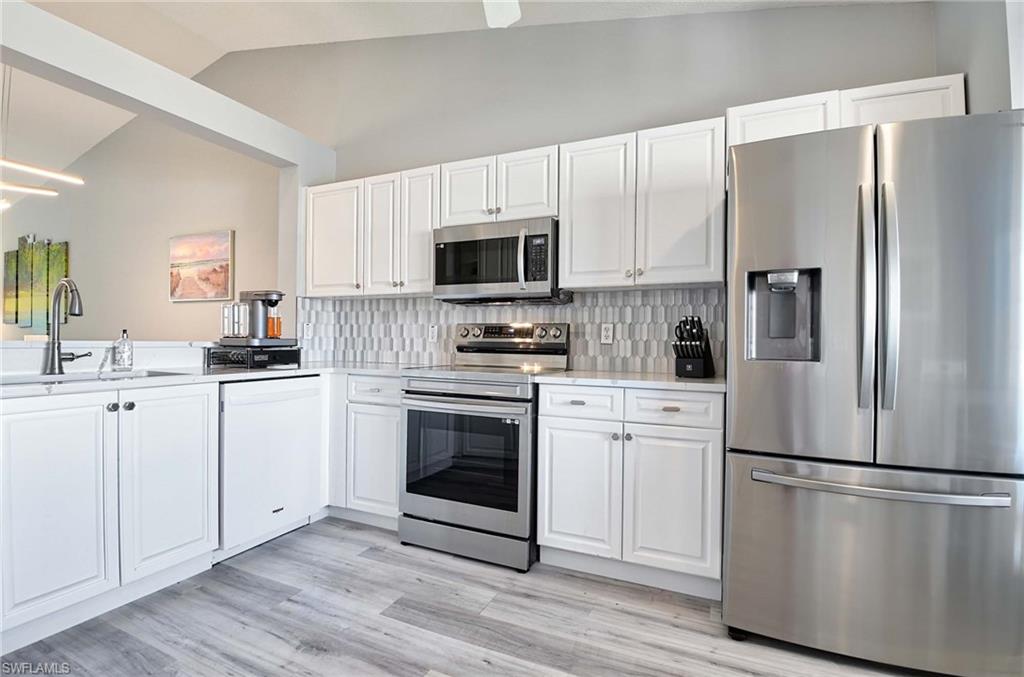 9022 Michael Circle, Unit 2210 Naples, FL 34113 - Photo 8 of 36 a kitchen with white cabinets and stainless steel appliances