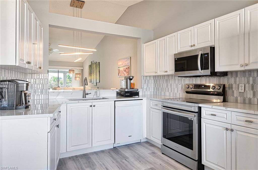 9022 Michael Circle, Unit 2210 Naples, FL 34113 - Photo 9 of 36 a kitchen with white cabinets and white appliances
