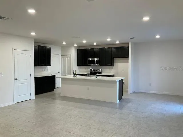 a view of kitchen with stainless steel appliances kitchen island granite countertop a stove a oven a sink and a cabinets