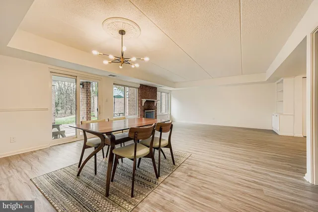 a dining room with wooden floor a chandelier a wooden table and chairs