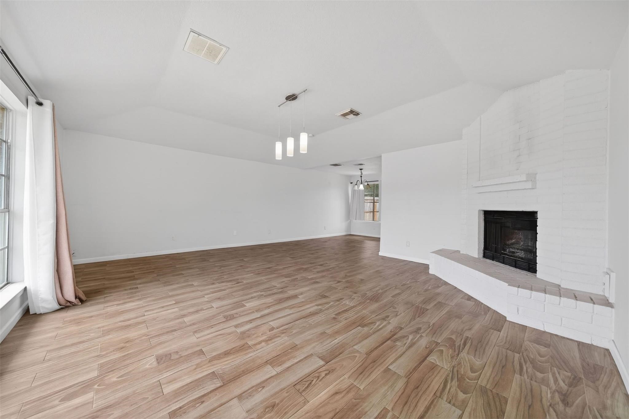 17002 Dew Drop Lane Houston, TX 77095 - Photo 2 of 24 an empty room with wooden floor and fireplace