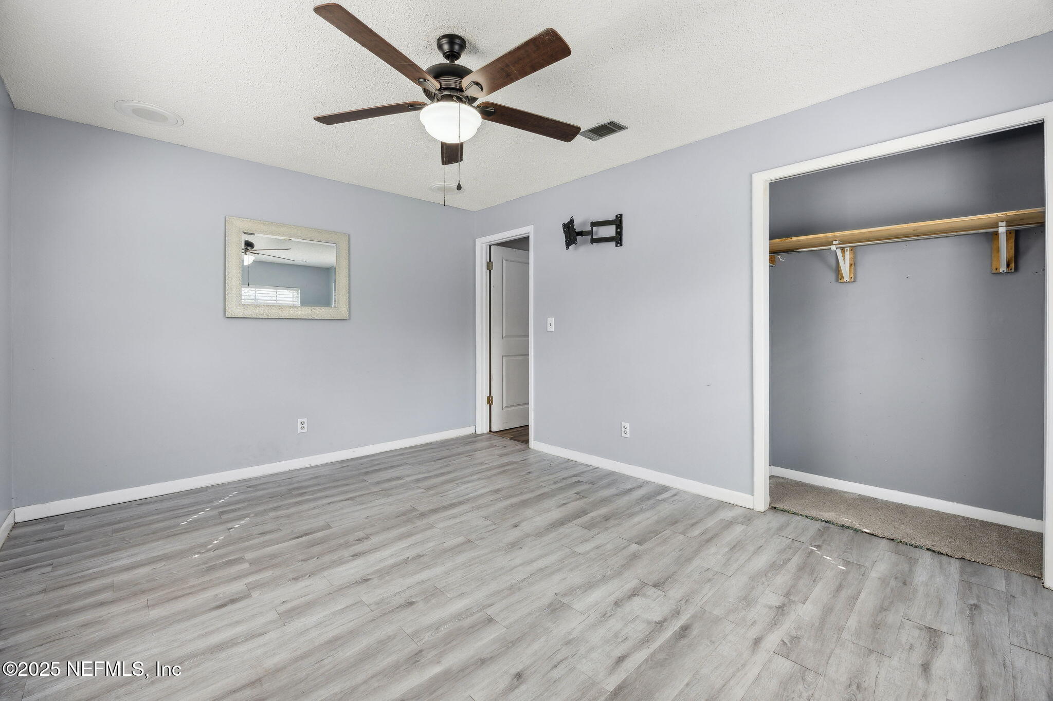 6305 Wuthering Heights Road Jacksonville, FL 32211 - Photo 48 of 52 an empty room with wooden floor and ceiling fan