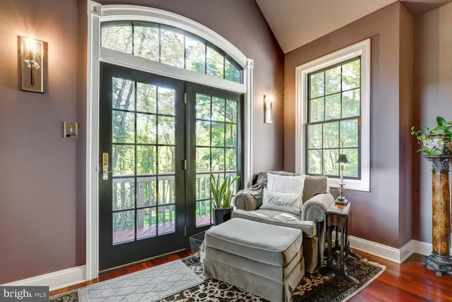 a bedroom with a bed a mirror on dresser and a large window