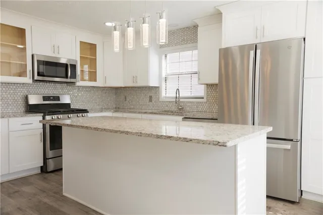 a kitchen with stainless steel appliances granite countertop a stove a sink and a refrigerator with wooden floor