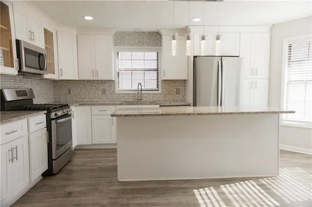 a kitchen with stainless steel appliances white cabinets and a refrigerator