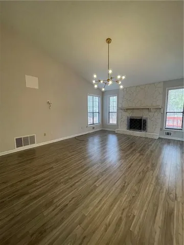 a view of a livingroom with a fireplace wooden floor and chandelier