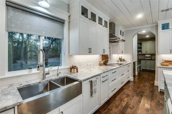 a kitchen with stainless steel appliances granite countertop a refrigerator a stove and a sink with wooden floor
