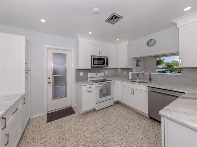 a kitchen with granite countertop white cabinets and stainless steel appliances