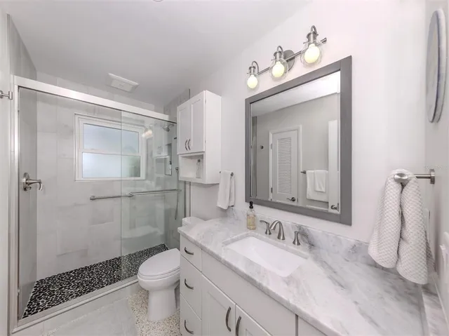 a bathroom with a sink a toilet and shower