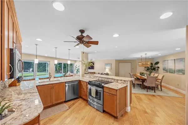 a kitchen with stainless steel appliances granite countertop a stove and a view of living room
