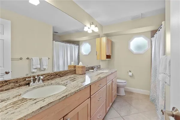 a bathroom with a granite countertop sink mirror and toilet