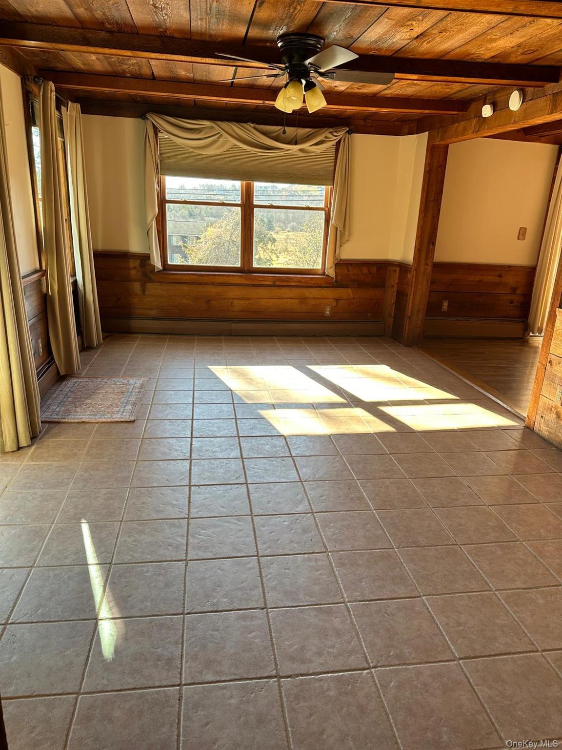 168 Pine Hill Road, Unit 1 Chester, NY 10918 - Photo 3 of 13 Tiled dining room featuring wood beam ceiling, ceiling fan, and wood detailing