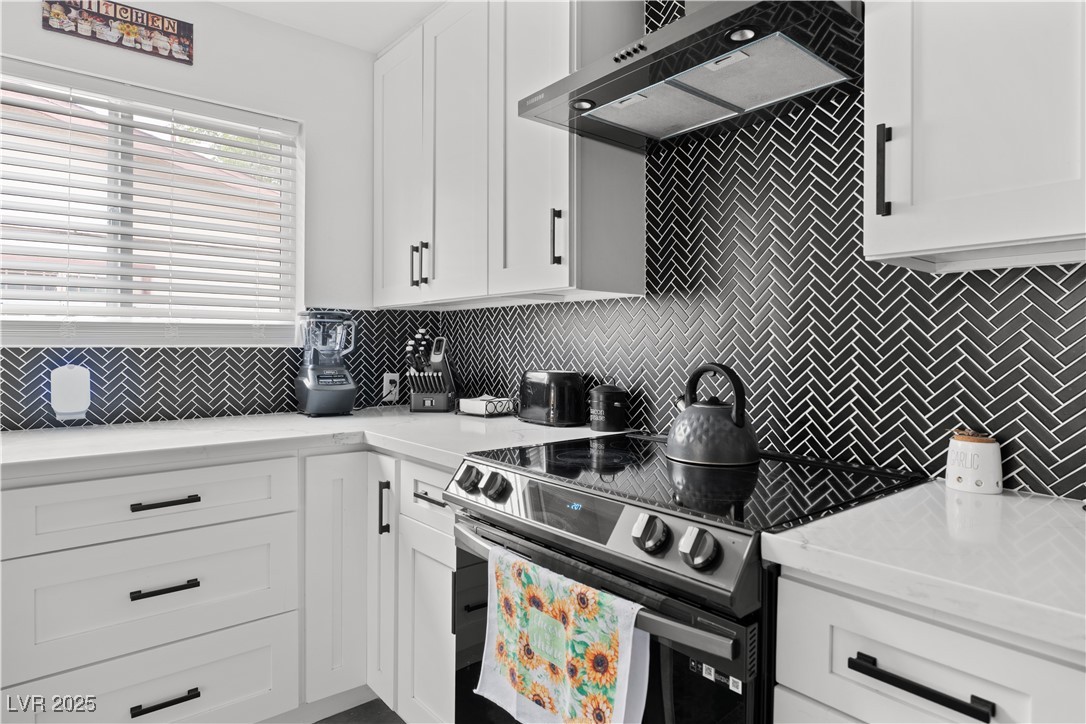 4231 Rimcrest Road Las Vegas, NV 89121 - Photo 13 of 52 Kitchen with stainless steel electric range, range hood, backsplash, white cabinetry, and light countertops