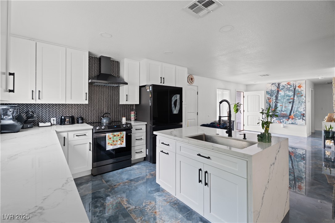 4231 Rimcrest Road Las Vegas, NV 89121 - Photo 16 of 52 Kitchen featuring range with electric cooktop, wall chimney range hood, freestanding refrigerator, decorative backsplash, and white cabinetry