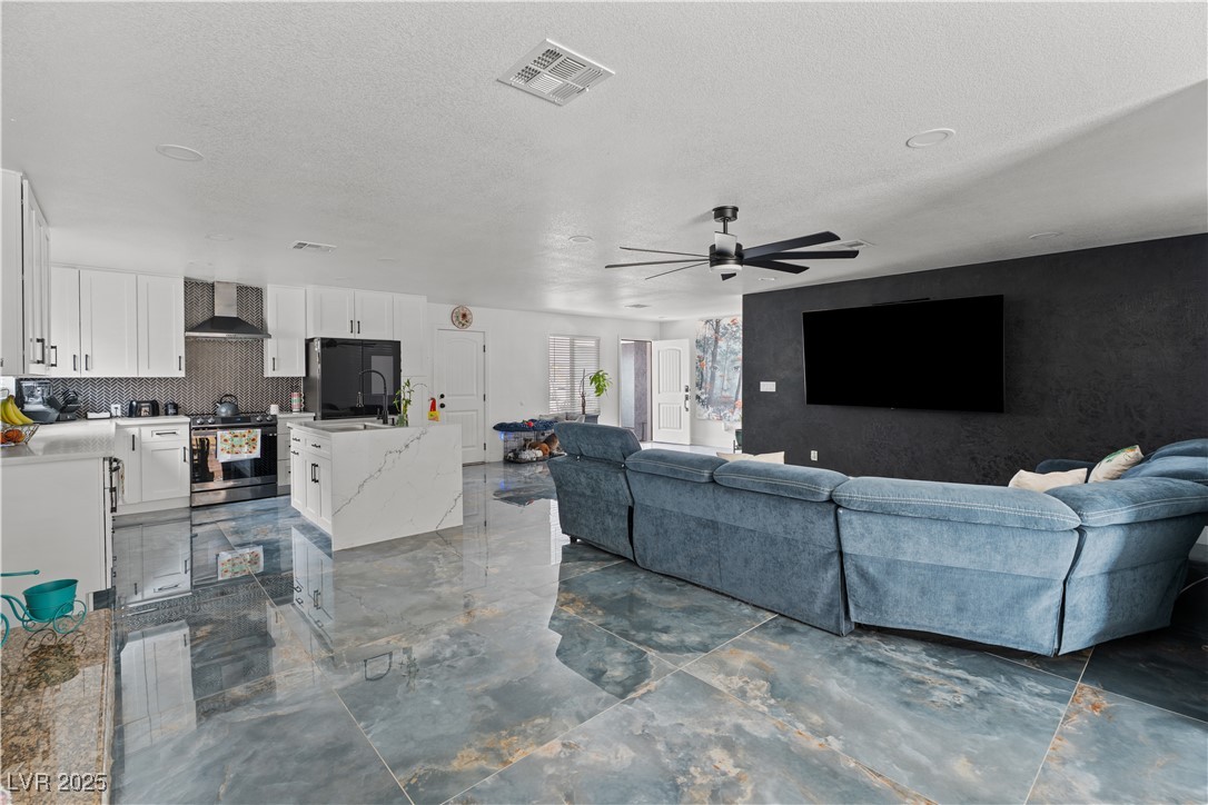 4231 Rimcrest Road Las Vegas, NV 89121 - Photo 17 of 52 Living room featuring a ceiling fan, a textured ceiling, and dark marble finish floors