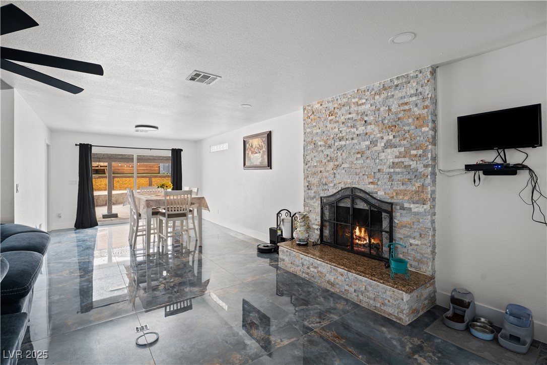 4231 Rimcrest Road Las Vegas, NV 89121 - Photo 19 of 52 Living area with a textured ceiling, a fireplace, a ceiling fan, and concrete flooring