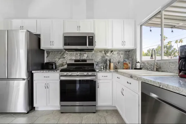 a kitchen with cabinets stainless steel appliances and a window