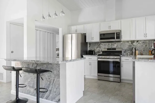 a kitchen with stainless steel appliances granite countertop a stove a sink and a microwave
