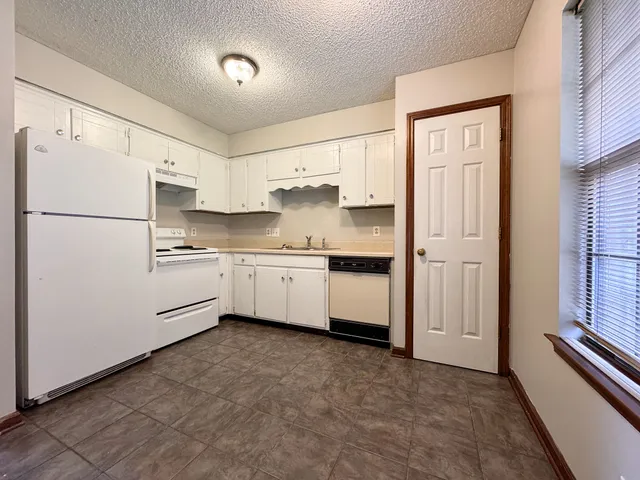 a kitchen with white cabinets and white appliances