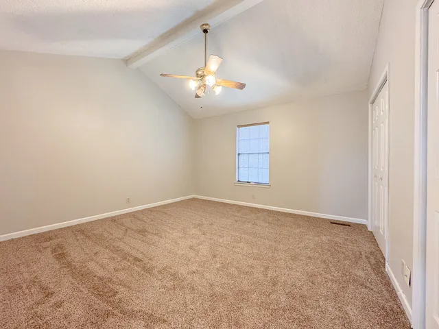 an empty room with a window and a chandelier fan