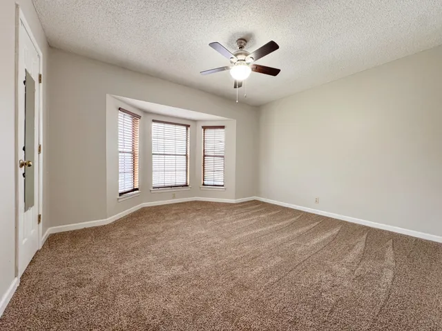 an empty room with windows and chandelier fan
