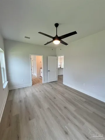 an empty room with wooden floor fan and windows