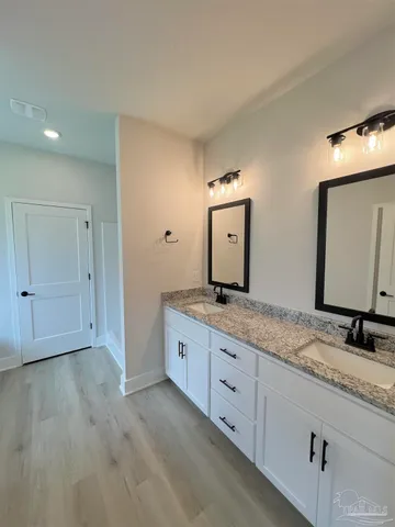 a bathroom with a granite countertop sink mirror and cabinets