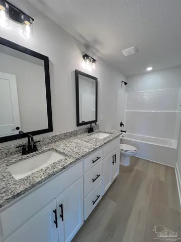 a bathroom with a granite countertop sink mirror and a bathtub