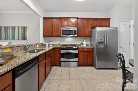 a kitchen with stainless steel appliances granite countertop a stove refrigerator and cabinets