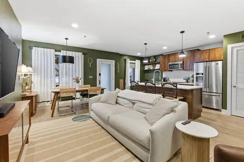 a living room with furniture a refrigerator and kitchen view