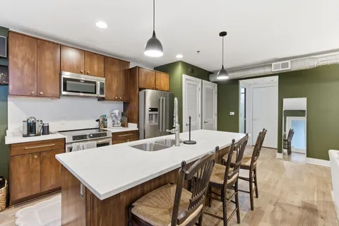a kitchen with stainless steel appliances a stove a refrigerator a sink a dining table and chairs