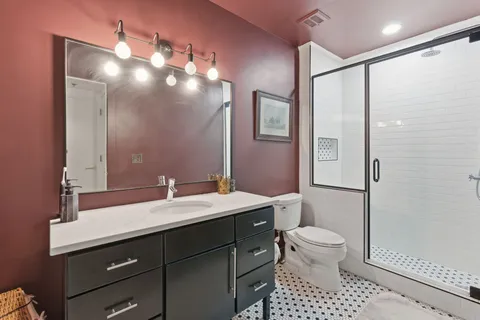 a bathroom with a sink a toilet a mirror and shower