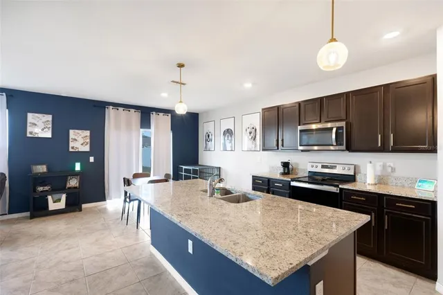 a kitchen with stainless steel appliances granite countertop a sink dishwasher a stove top oven a refrigerator with island and chairs